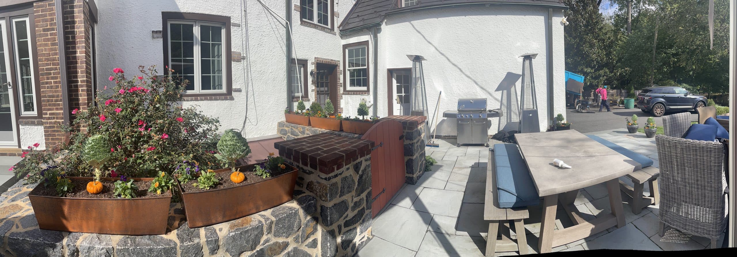 Fieldstone terrace with a built-in grill, dining table, corten planters, and bluestone paving